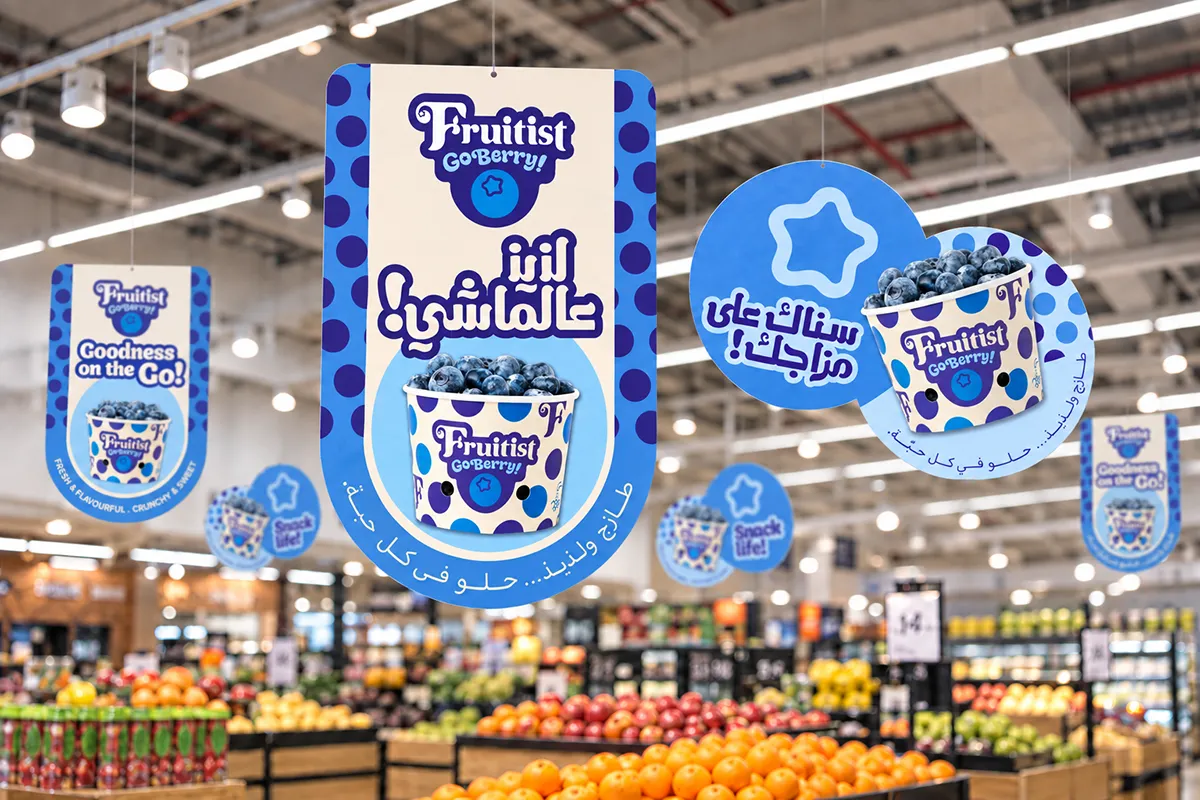 Illustrative supermarket mockup of Fruitist GoBerry! hanging danglers, with expressive Arabic headlines and English campaign messages.