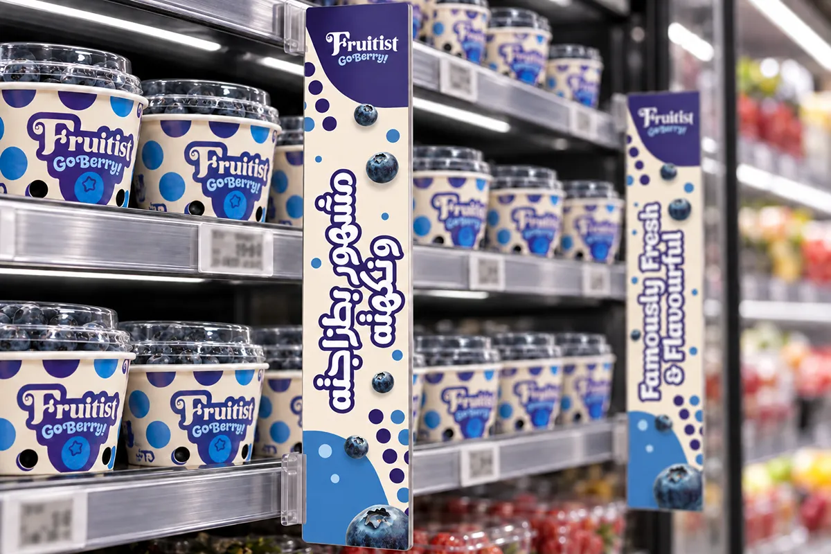 Illustrative mockup of cream-and-purple Fruitist shelf dividers with Arabic lettering and ‘Famously Fresh & Flavourful’ English messaging beside blueberry packs.
