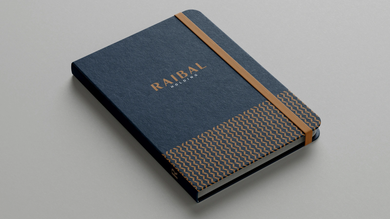Navy Raibal notebook mockup with a bronze logo, lower pattern band and warm-toned elastic closure.